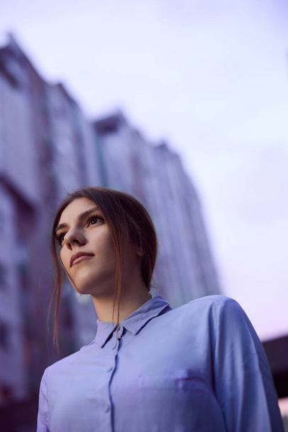 A teenage girl stands at the urban exterior surrounded by skyscrapers. - Fotografie, Obrázek