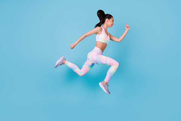 Teljes hosszúságú fotó céltudatos erős nő öltözött sport jelmez ugrás fel fut gyorsan elszigetelt kék háttér. - Fotó, kép