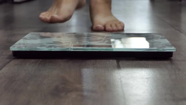 Nainen vaa 'alla mittaa painoa. Tyttö jalat askel kylpyhuone mittakaavassa. Fitness Diet Nainen Jalat Seisoo Painavat vaa 'at Huoneessa. Nainen laihduttaminen tarkkailun BMI laihtuminen. Paljain jaloin mittauselin - Materiaali, video