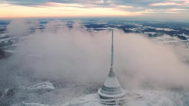 Edificio de hotel en torre Jested cubierto de densa nube de niebla en el día de invierno. Arquitectura futurista moderna con aguja construida sobre vista aérea de montaña - Metraje, vídeo