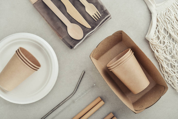 Set of eco-friendly tableware and kraft paper food packaging on light concrete background. Street food paper packaging - cups, plates, straws, containers and cutlery.  - Foto, imagen