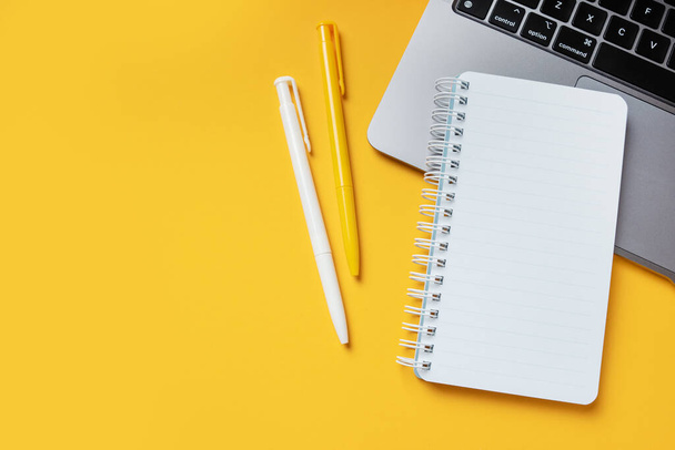 Yellow office desktop background with mockup empty notepad, modern laptop, pens and empty place for copy space. Freelance or working at home concept. - Foto, Bild