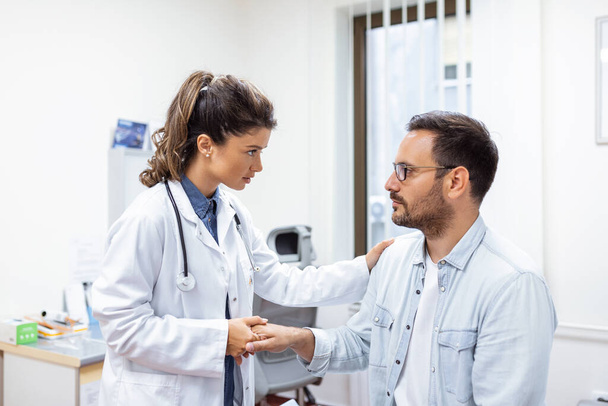 Młoda kobieta lekarz trzymać rękę kaukaski mężczyzna pacjent dać komfort, wyrazić współczucie opieki zdrowotnej, pomoc medyczna zaufanie wsparcie zachęcić uspokoić bezpłodnego pacjenta podczas wizyty lekarskiej - Zdjęcie, obraz