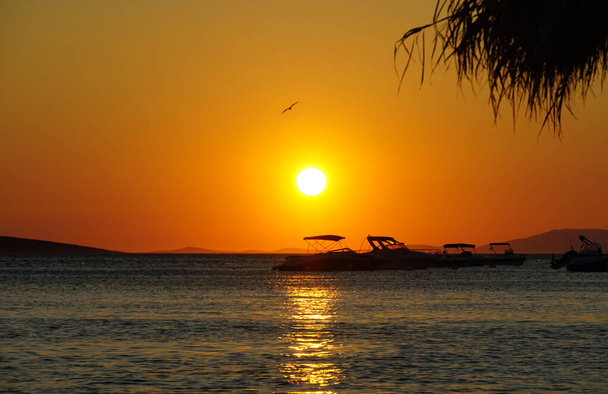 美しい穏やかなオレンジの夕日で浮かぶボートと海の景色 - 写真・画像