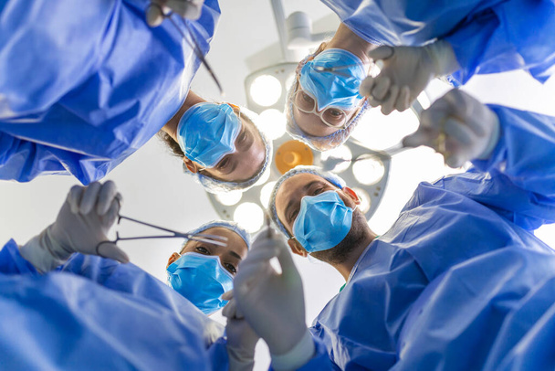 Chirurgen die boven de patiënt stonden voor de operatie. Multi-etnische gezondheidswerkers die de patiënt opereren in de operatiekamer. - Foto, afbeelding