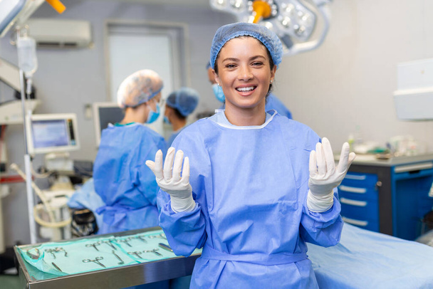 Porträt einer jungen Chirurgen-Ärztin umgeben von ihrem Team. Gruppe von Chirurgen im Operationssaal. - Foto, Bild