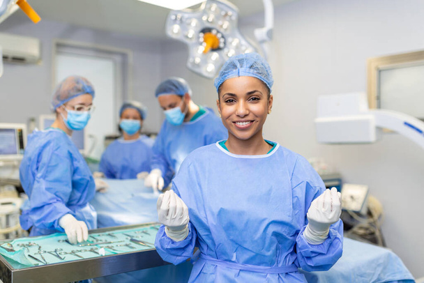 Portret chirurga stojącego na sali operacyjnej, gotowego do pracy nad pacjentem. African American Kobieta pracownik medyczny chirurgiczny mundur w sali operacyjnej. - Zdjęcie, obraz