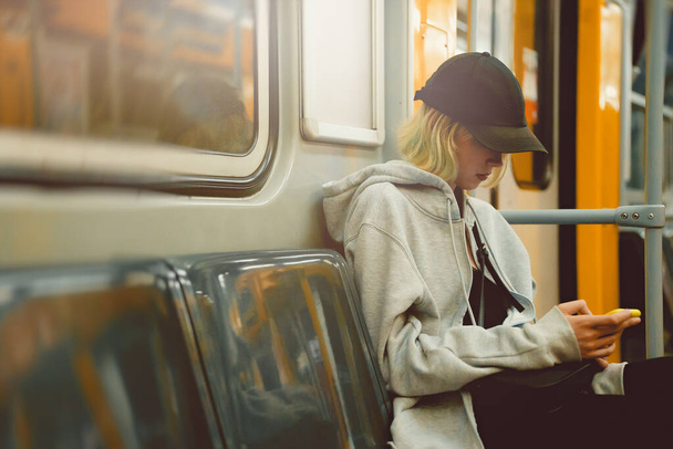 Nastolatka z przejażdżkami smartfonem w pociągu metra. - Zdjęcie, obraz