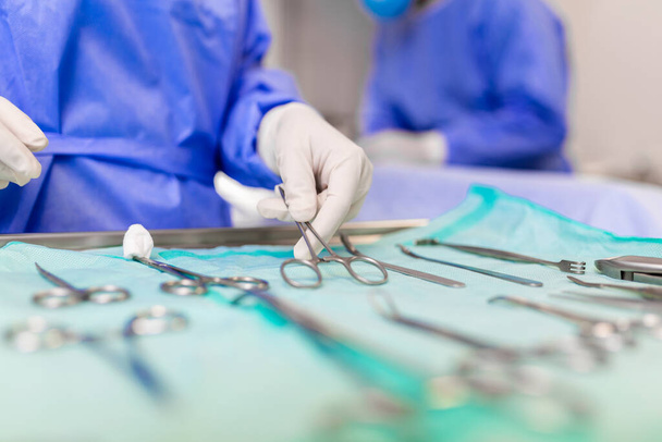 Хирург забирает хирургический инструмент из подноса. Хирург готовится к операции в операционной. Он в больнице.. - Фото, изображение