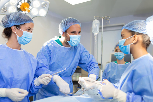 Chirurgové muži a ženy v jednom týmu během operace nad operačním stolem, lékaři v moderním vybavení provádějí onkologickou operaci - Fotografie, Obrázek