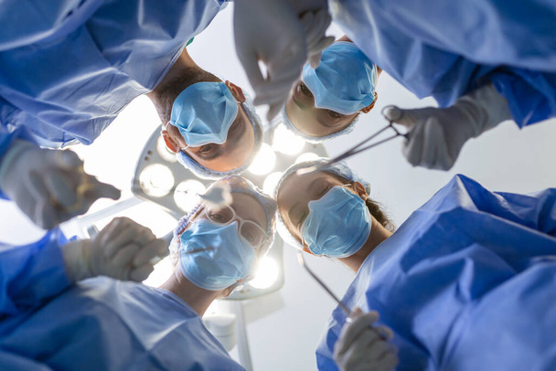 Surgeons standing above of the patient before surgery. Multi-ethnic healthcare workers performing surgery on patient at operation theater. - Foto, Bild