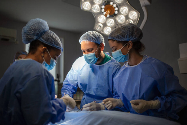 Chirurgiens opérant en salle d'opération. chirurgie d'augmentation mammaire dans la salle d'opération chirurgien outils implant. Concept de soins médicaux. - Photo, image