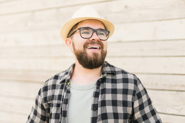 Laughing attractive man wearing hat over wooden background - emotion and vacation travel holidays - Fotoğraf, Görsel