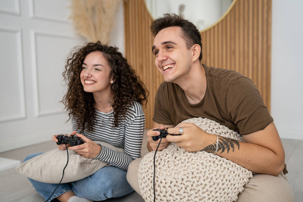 Δύο άτομα ζευγάρι άντρας και γυναίκα φίλος και φίλη σύζυγος και γυναίκα ή φίλοι παίζουν κονσόλα βιντεοπαιχνίδια κρατήσει χειριστήριο joystick ευτυχισμένο χαμόγελο συναισθηματική χειρονομία αντίδραση οικογενειακή αναψυχή αντίγραφο χώρου - Φωτογραφία, εικόνα