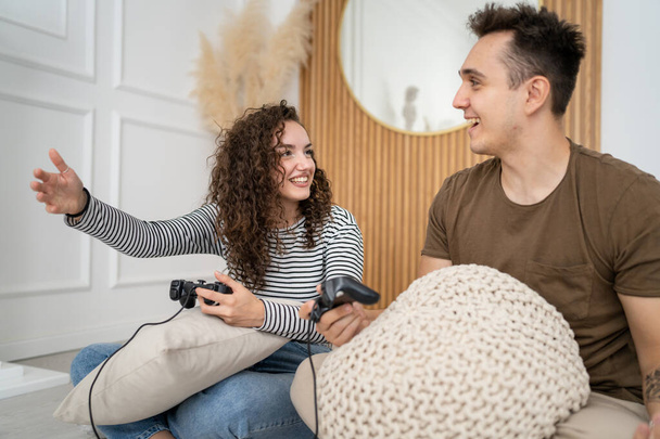 Két ember pár férfi és nő barát és barátnő férj és feleség vagy barátok játék konzol videojátékok tartani joystick vezérlő boldog mosoly érzelmi gesztus reakció család szabadidő másolat tér - Fotó, kép