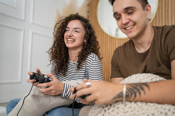 Twee mensen paar man en vrouw vriend en vriendin man en vrouw of vrienden spelen console video games houden joystick controller gelukkig glimlach emotioneel gebaar reactie familie vrije tijd kopiëren ruimte - Foto, afbeelding