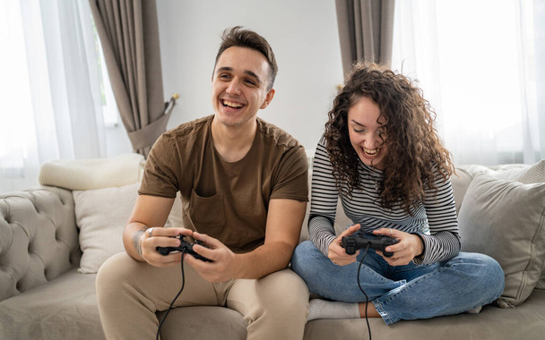 Due persone coppia uomo e donna fidanzato e fidanzata marito e moglie o amici giocare console videogiochi tenere joystick controller felice sorriso emotivo gesto reazione famiglia tempo libero copia spazio - Foto, immagini