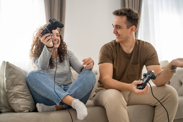 Deux personnes couple homme et femme petit ami et petite amie mari et femme ou amis jouer console jeux vidéo tenir joystick contrôleur heureux sourire réaction geste émotionnel famille loisirs copie espace - Photo, image