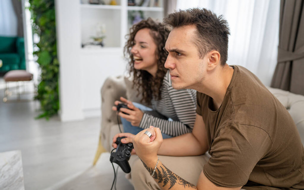 Két ember pár férfi és nő barát és barátnő férj és feleség vagy barátok játék konzol videojátékok tartani joystick vezérlő boldog mosoly érzelmi gesztus nyertes reakció családi másolat tér - Fotó, kép