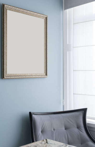 Poltrona azul grande pela janela e moldura de imagem vazia. Foto de alta qualidade - Foto, Imagem
