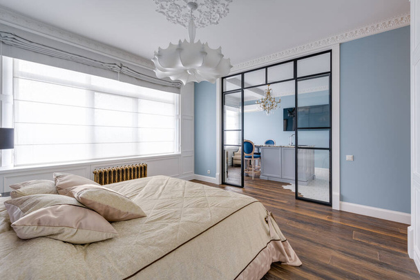 Gran habitación luminosa con paredes azules y una enorme lámpara de araña blanca y pared de cristal. Foto de alta calidad - Foto, Imagen