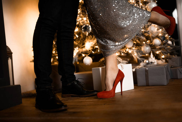 Nahaufnahme der Beine eines Mannes und einer Frau in Schuhen auf dem Hintergrund der Weihnachtsdekoration - Foto, Bild