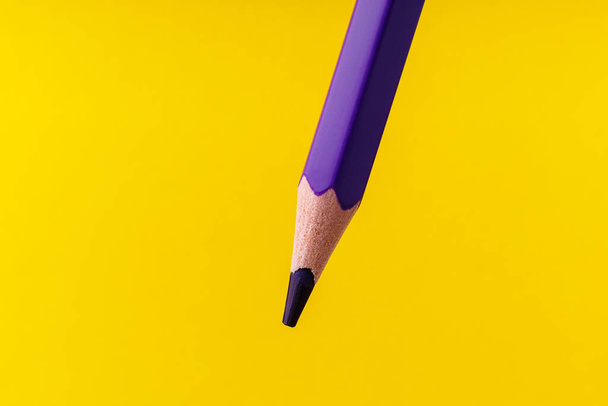 Colored pencil close-up with selective focus on the stylus and a blurred yellow background. Copy space for text. - Foto, Imagem