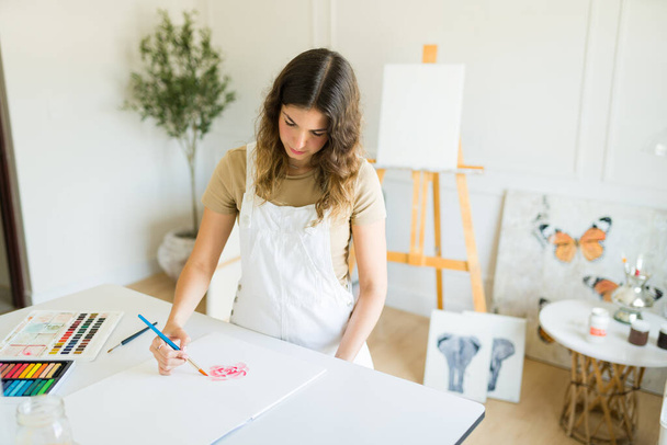 Δημιουργική νεαρή γυναίκα καλλιτέχνης αναζητούν εμπνευσμένη, ενώ δημιουργώντας ένα νέο πίνακα στο εργαστήριο  - Φωτογραφία, εικόνα