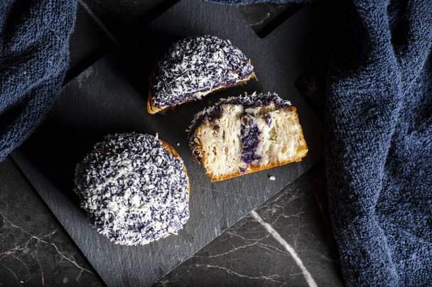 A cruffin is a hybrid of a croissant and a muffin. The pastry is made by proofing and baking laminated dough in a muffin mould. The cruffin is then filled with various creams, jams or curds, and then garnished. This cruffin has Ube filling. - Foto, Bild