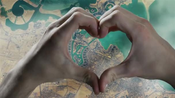 Manos mostrando la forma del corazón sobre una vista satelital de Doha en la costa este de Qatar. Elementos de este vídeo suministrado por la NASA.   - Imágenes, Vídeo