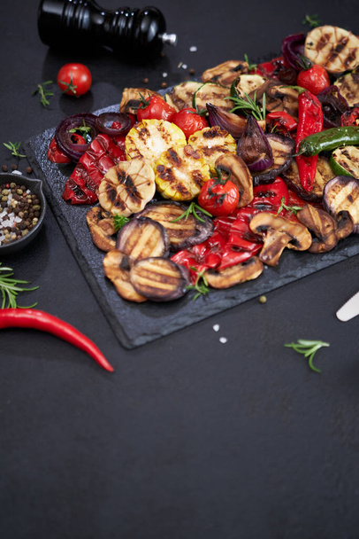 Grilled vegetables mix on a stone serving board - zucchini eggplant onions corn mushroom tomato. - Foto, afbeelding