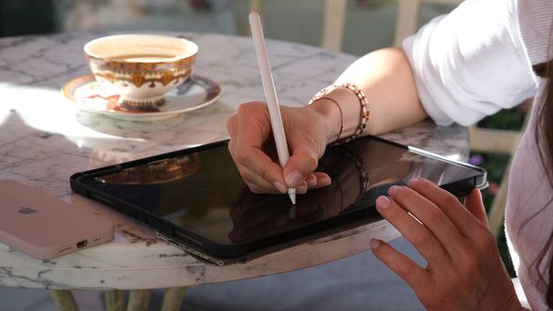 Meisje ontwerper zit in een cafe met een tablet - Foto, afbeelding