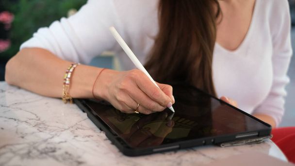 Meisje ontwerper zit in een cafe met een tablet - Foto, afbeelding