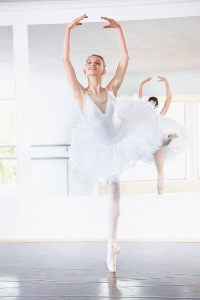 An accomplished ballerina. a ballerina rehearsing in a studio with a mirror behind her - Foto, immagini