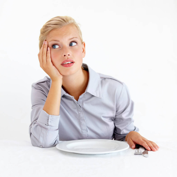 Ive been waiting for ages. Bored young woman sitting in front of an empty plate - Photo, Image