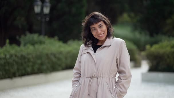 南アメリカの若い女性がカメラで笑ってジャケットを着ている。屋外に立つラテン語の楽しい女の子 - 映像、動画