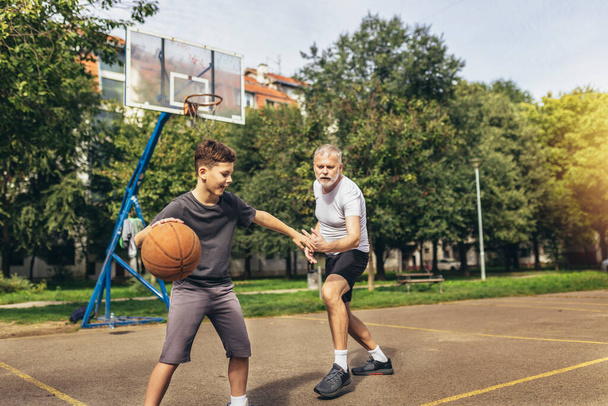 Padre e figlio si divertono a giocare a basket su un campo sportivo - Foto, immagini