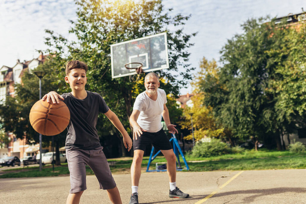Apa és fia élvezi kosárlabda játék egy sportpályán - Fotó, kép