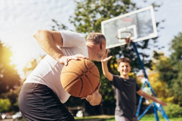 Πατέρας και γιος απολαμβάνουν αγώνα μπάσκετ σε αθλητικό γήπεδο - Φωτογραφία, εικόνα