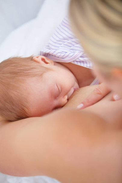 Vreedzaam moment. Hoge hoek schot van een moeder borstvoeding haar pasgeboren baby - Foto, afbeelding