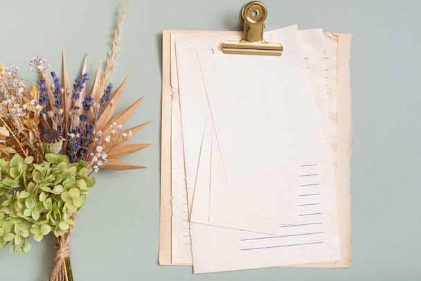 Renkli arka planda boş bir kağıt parçası ve bir buket kuru çiçek. Düz yatıyordu. - Fotoğraf, Görsel