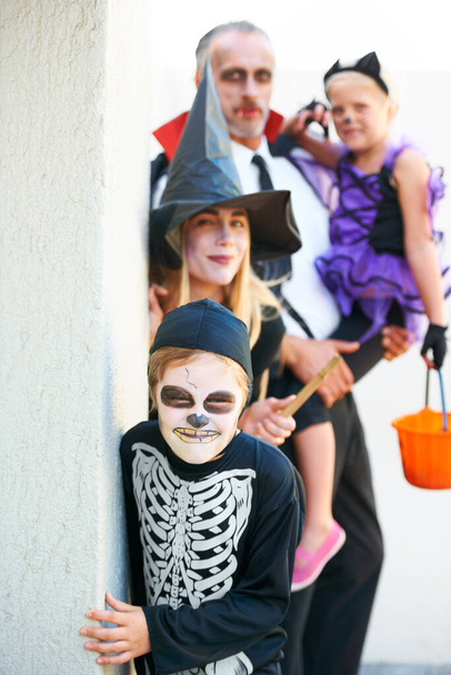 Se dirigen a tu puerta. Una linda familia vestida para Halloween acercándose sigilosamente para asustarte - Foto, imagen