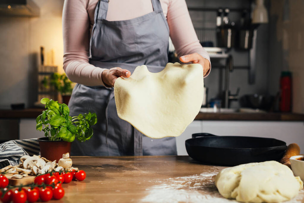 close up of woman preparing dough for pizza in home kitchen - Фото, изображение