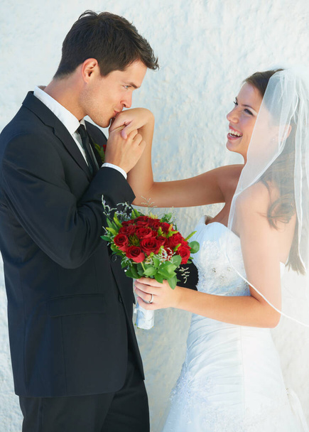 Bewunderung für seine neue Frau. Ein schöner Bräutigam küsst seine Bräute liebevoll die Hand - Foto, Bild