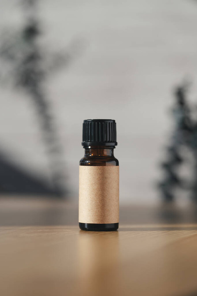 Amber bottle with craft label filled serum, tonic or essential oil on wooden table. Beauty concept for face and body care. Soothing cbd oil. Alternative Medicine. - 写真・画像