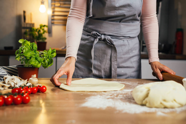 close up of woman preparing dough for pizza in home kitchen - Foto, Bild