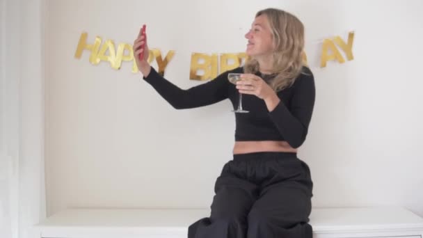 Szczęśliwa kobieta pije wino w urodziny i rozmawia przez wideo link z jej telefonu. - Materiał filmowy, wideo