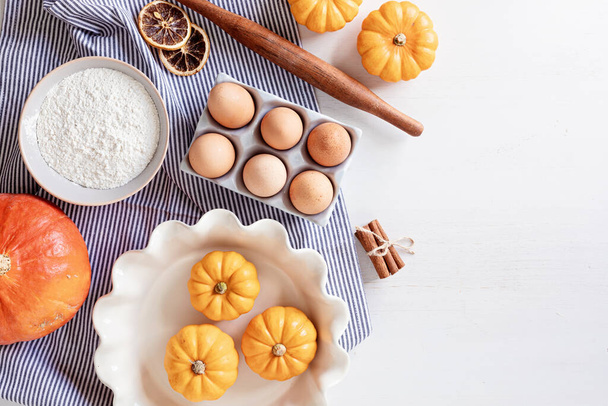 Fall pie baking ingredients with pumpkins, nuts, seasonal spices and tools. Pumpkin pie recipe idea. Thanksgiving and autumn holidays celebration concept. Top view, flatlay - Photo, Image