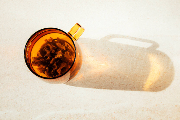 Caneca de vidro transparente laranja com chá verde quente, sombra e reflexão sobre fundo de pedra leve. Vista superior - Foto, Imagem