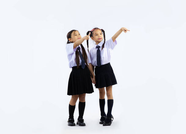 Back to school concept. Junior school asian cute international student in uniform posing finger pointing on white background. - Foto, immagini